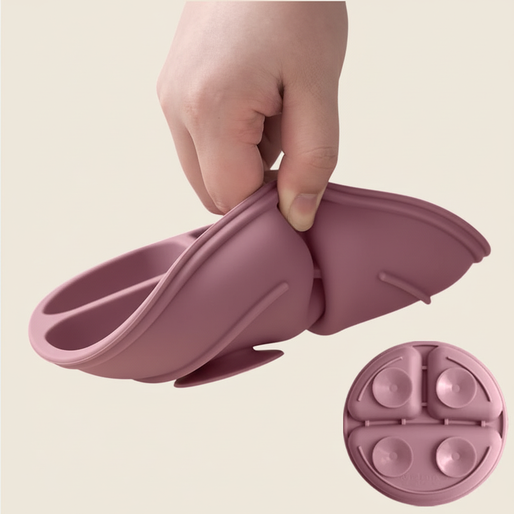 Hand flexing dusty pink silicone divided plate showing soft flexible material and suction cup base