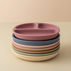 Stack of silicone divided baby plates in multiple earthy tones including dusty pink, slate blue and sage