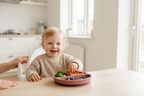 Happy toddler in white high chair eating from clay silicone divided suction plate